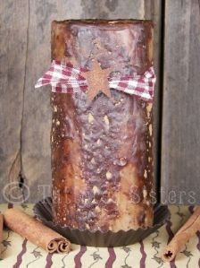 a candle with cinnamon sticks around it on top of a table cloth and wooden background