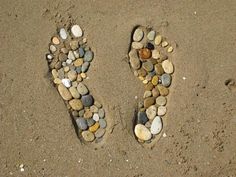 there is a pair of shoes made out of rocks in the sand on the beach