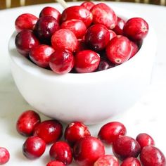 a white bowl filled with cranberries on top of a table