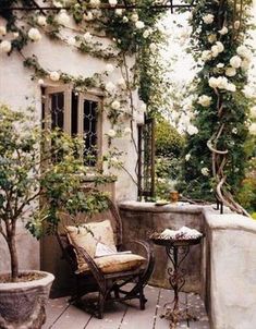 an outdoor patio with chairs, tables and potted plants on the side of it