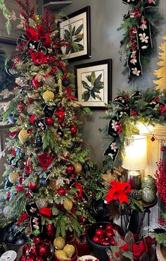 a christmas tree decorated with red, gold and green ornaments in front of pictures on the wall