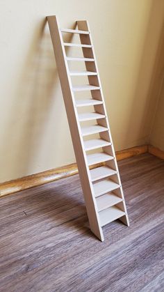 a white book shelf sitting on top of a hard wood floor next to a wall