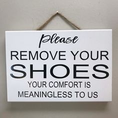 a sign hanging on the wall that says please remove your shoes your comfort is meanness to us