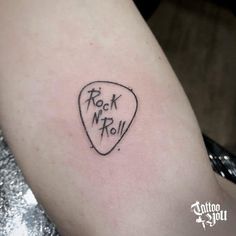 a rock n roll guitar pick tattoo on the arm