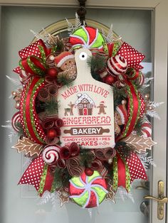 a christmas wreath hanging on the front door of a bakery with red and green ribbons