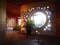 a circular window in the middle of a stone wall with plants and potted plants