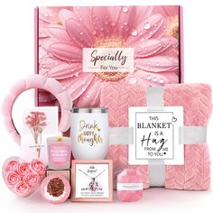 a pink gift box with flowers, candles and other items