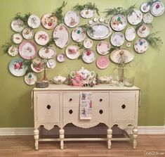 there is a table with many plates on it and a wall hanging above the table