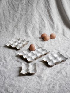 three eggs are sitting in an egg tray on a white tablecloth next to some broken ones