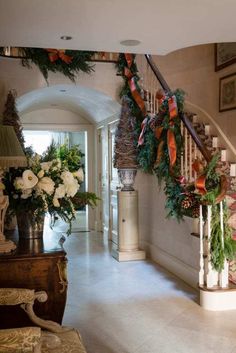 a staircase decorated for christmas with wreaths and flowers on the bannister railing