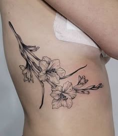 a woman's stomach with flowers and leaves tattooed on her side ribcage