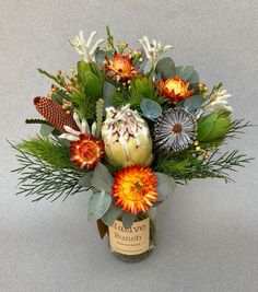 a vase filled with lots of flowers and greenery on top of a gray surface