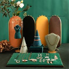 an assortment of jewelry sitting on top of a green table next to a vase with flowers