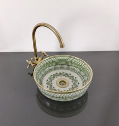 a green and white bowl sink sitting on top of a black counter next to a faucet