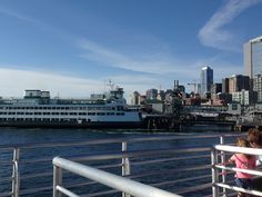 two children looking at a large ferry boat in the water next to a cityscape