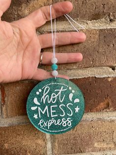 a hand holding a green ornament that says, not mess express on it