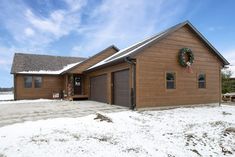 a house with a wreath on the front door and snow on the ground around it