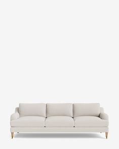 a white couch sitting on top of a white floor next to a wall with a wooden frame