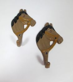 two brown and black horse shaped magnets on a white surface