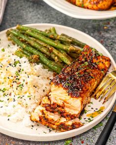 a white plate topped with chicken, rice and asparagus next to a fork