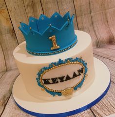 two tiered cake decorated with blue and white frosting, topped with a tiara