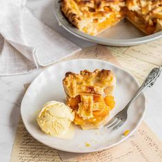 a piece of pie on a plate with ice cream and a fork next to it