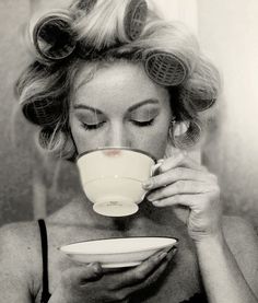 a black and white photo of a woman drinking from a cup