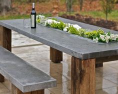 a bottle of wine sitting on top of a wooden table next to a park bench