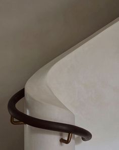 a curved stair rail in the corner of a white wall with black metal handrails