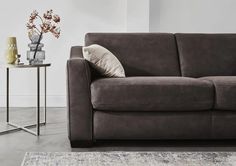 a gray couch sitting on top of a rug next to a table with vases