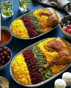 two plates filled with food on top of a table next to bowls of fruit and vegetables