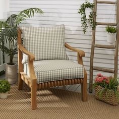 a wooden chair sitting on top of a rug next to a potted plant and a ladder