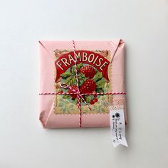 a package wrapped in pink paper and tied up with a red ribbon that says framboise