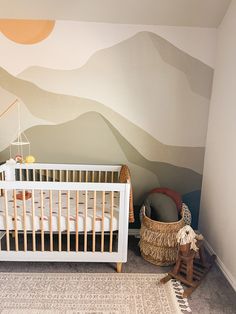 a baby's room with mountains painted on the wall and a crib next to it