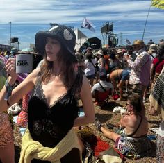 a woman in a black dress and hat holding a coffee cup at an outdoor music festival