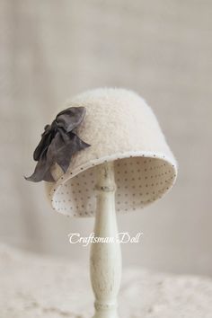 a white hat with a black bow on it's brimmed hat stand