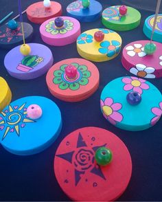 several colorful wooden discs with pins and flowers on them sitting on a black table top