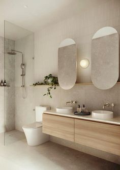 a modern bathroom with two sinks and a toilet in the middle, along with a shower