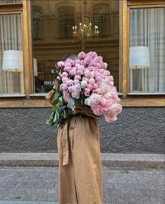 a woman holding a bunch of pink flowers