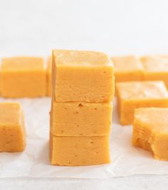 several pieces of yellow fudge sitting on top of wax paper next to each other