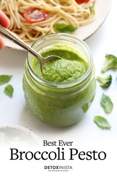 the best ever broccoli pesto is in a jar with a spoon next to it