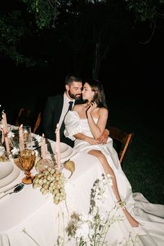 a man and woman sitting at a table with candles in front of them on their wedding day