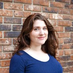 a woman standing in front of a brick wall