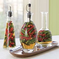 three glass vases filled with different types of vegetables on a tray next to each other