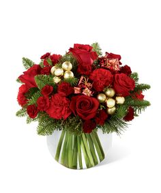 a vase filled with red roses and greenery