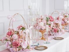 a table topped with lots of vases filled with pink flowers and candles next to each other