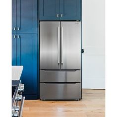 a stainless steel refrigerator in a kitchen with blue cabinets