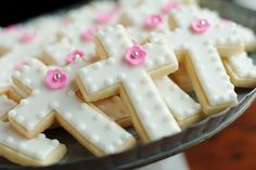 decorated cookies are arranged in the shape of crosses on a platter with pink and white decorations