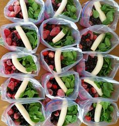 several plastic containers filled with fruit and veggies on top of a wooden table