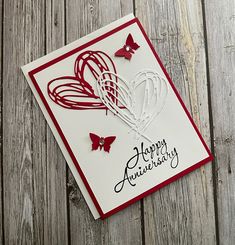 a happy anniversary card with red and white paper butterflies on wood planked flooring